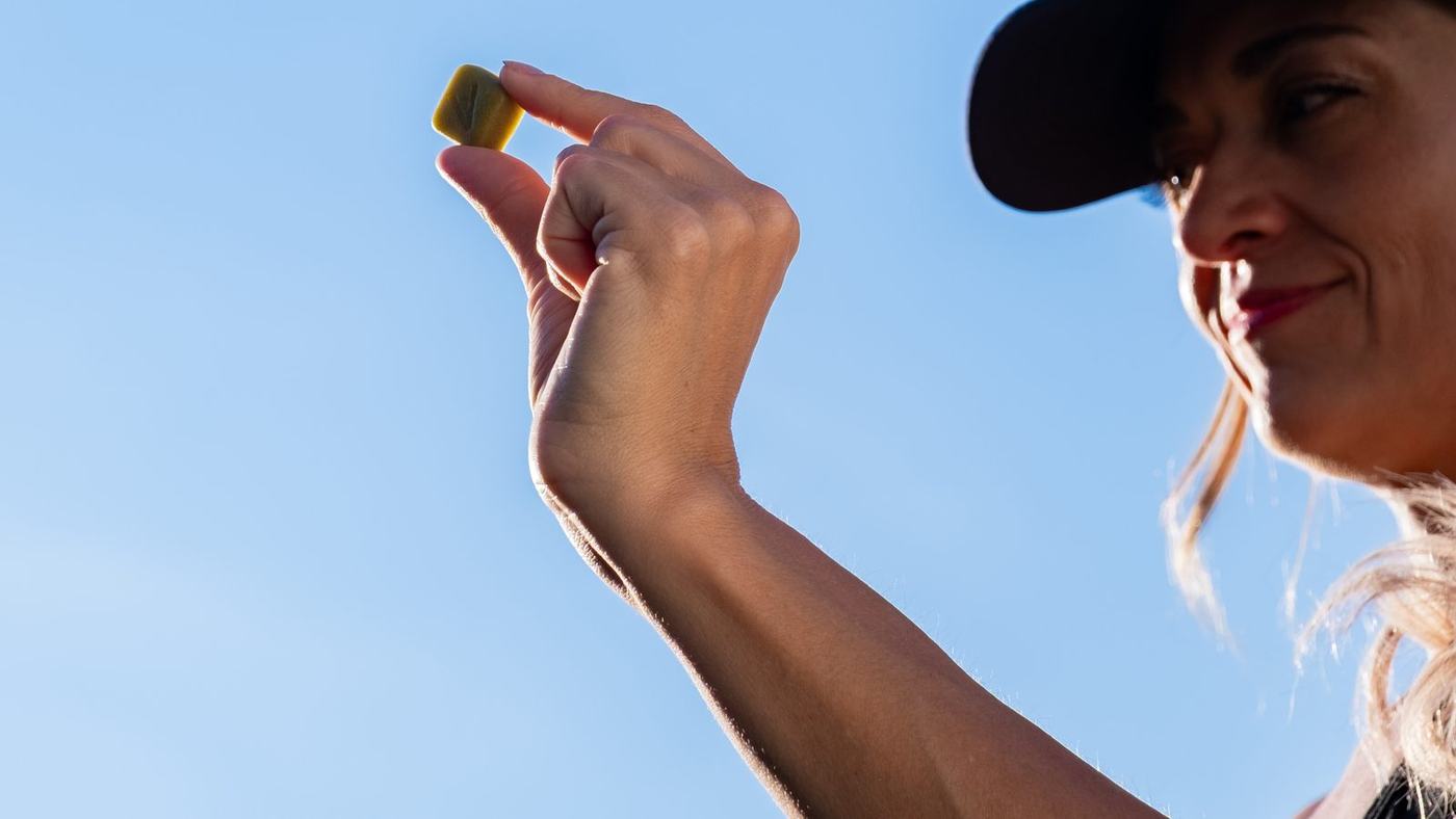 A single gummy held up against the sky